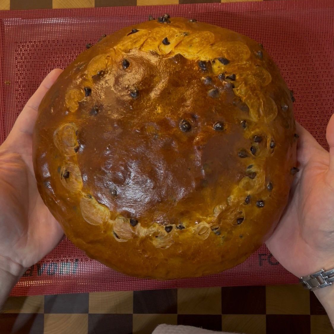 Cramique al cioccolato intero appena sfornato, con una crosta dorata e i classici tagli a croce 