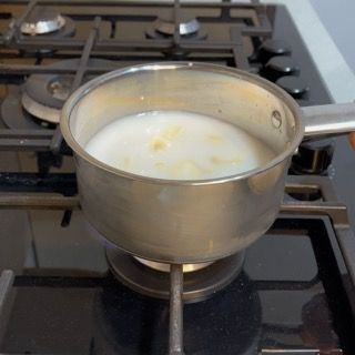 Pentolino sul fuoco con l'aglio in acqua e latte che raggiunge l'ebollizione.