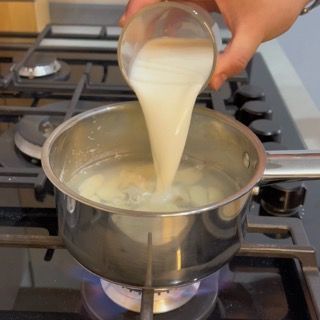 Reinserimento dell'aglio nel pentolino per avviare il processo della crema di aglio ricetta originale.