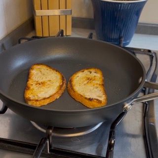 Due fette di pane stanno cuocendo in una padella sul fornello
