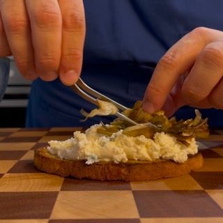 Una persona sta spalmando del formaggio cremoso su un pezzo di pane