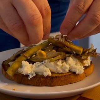 Una persona sta mettendo le verdure su un panino su un piatto