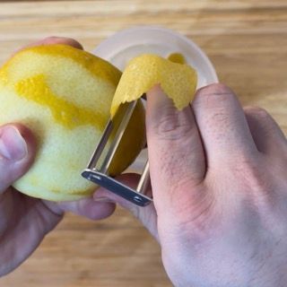 Una persona sta sbucciando un limone con un pelapatate