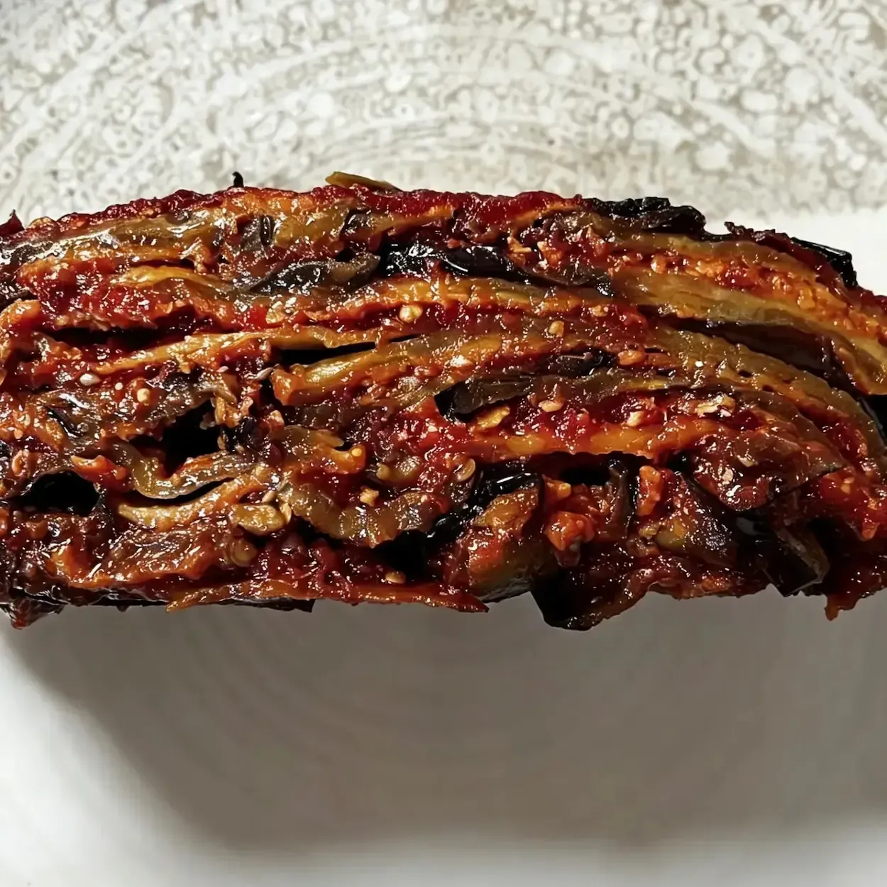 Dettaglio della fetta compatta di parmigiana di melanzane fritte stratificata con sugo di pomodoro e