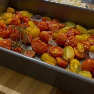 Una padella piena di pomodori e peperoni su un tavolo di legno.