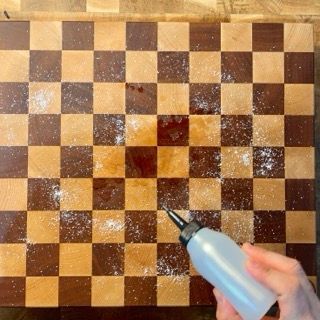 Una persona sta spruzzando qualcosa su un tagliere a scacchi