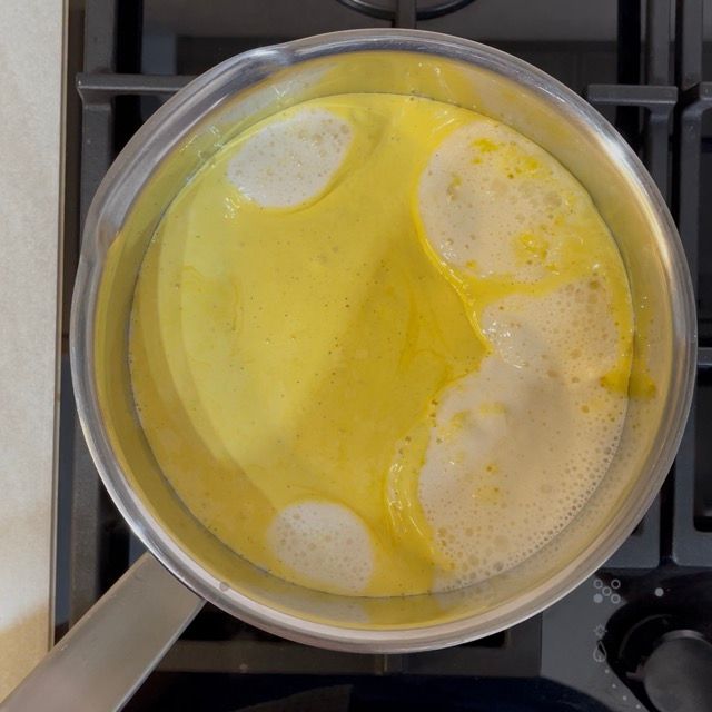 Frusta che mescola energicamente la crema pasticcera sul fuoco.