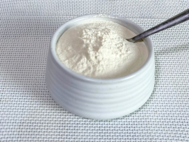 Una ciotola di latte in polvere con un cucchiaio dentro.