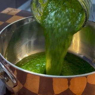 Trasferimento della purea verde smeraldo dal boccale del frullatore a un pentolino.