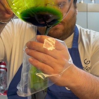 Travaso dell'olio verde filtrato all'interno di una sac à poche da pasticceria.
