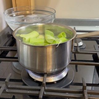 Immersione delle foglie di porro nell'acqua bollente per iniziare la sbollentatura.