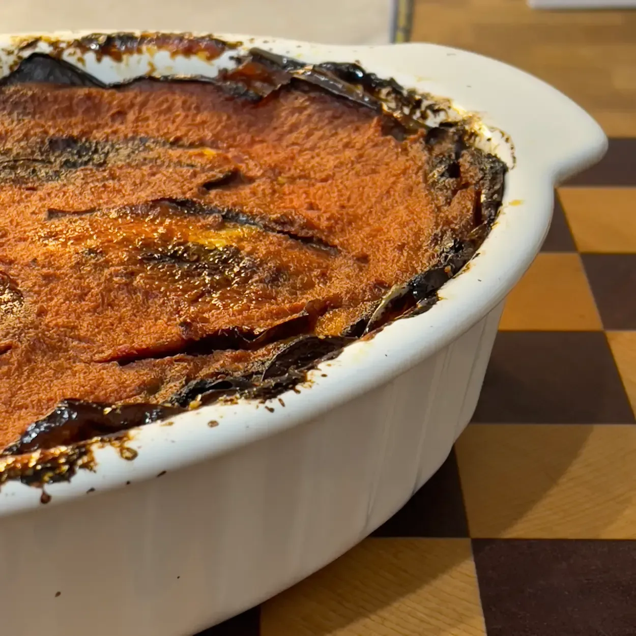 Pirofila fumante di parmigiana di melanzane al forno croccante, la ricetta originale della nonna con fior di latte.