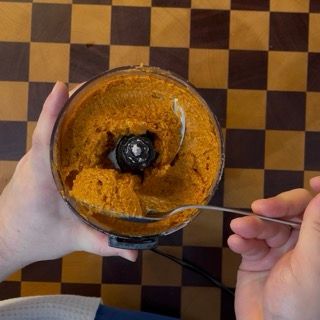 Trasferimento del pesto rosso fatto in casa in una ciotola capiente per la ricetta della pasta al tonno fredda.