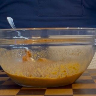 Versamento dei fusilli appena scolati direttamente nella ciotola capiente con il pesto rosso cremoso e l'acqua.