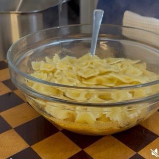 Mescolamento accurato dei fusilli nella ciotola per distribuire uniformemente il pesto rosso e renderli cremosi.