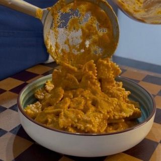 Impiattamento dei fusilli cremosi al pesto rosso prima dell'aggiunta del pesce per la pasta al tonno fredda.