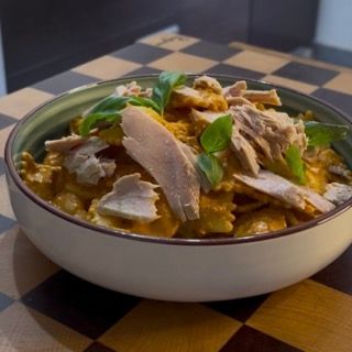 Decorazione con foglioline di basilico fresco della gustosa pasta fredda con pesto di pomodori secchi e tonno.