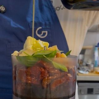 Versamento di olio extravergine di oliva a filo nel mixer per emulsionare il pesto rosso di pomodori secchi.