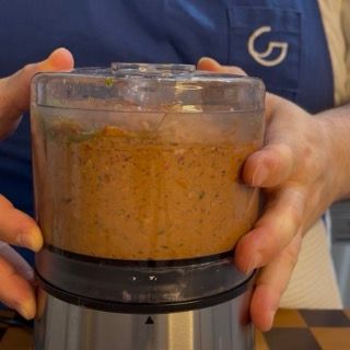 Aggiunta di acqua di cottura nel mixer per rendere il pesto rosso perfetto per la pasta fredda cremosa al tonno.