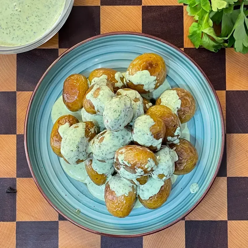 patate arrosto in padella croccanti e dorate, condite con ciuffetti di rosmarino e condite alla fine con una salsa verde alle erbe per delle patate arrosto perfette.
