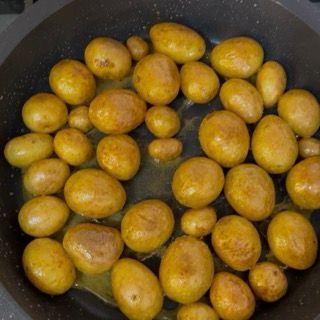Risultato in padella delle patate arrosto in padella croccanti e con la buccia dorata.