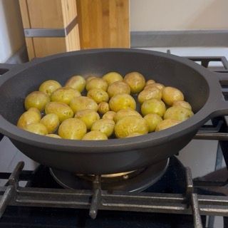 Versamento dell'acqua nella padella calda fino a raggiungere la metà dell'altezza delle patate.