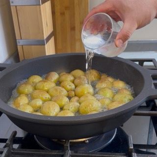 Dettaglio delle patate novelle che iniziano a sobbollire nell'acqua per creare delle patate arrosto in padella veloci.