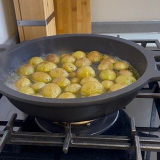 Dettaglio delle patate novelle che iniziano a sobbollire nell'acqua per creare delle patate arrosto in padella veloci.