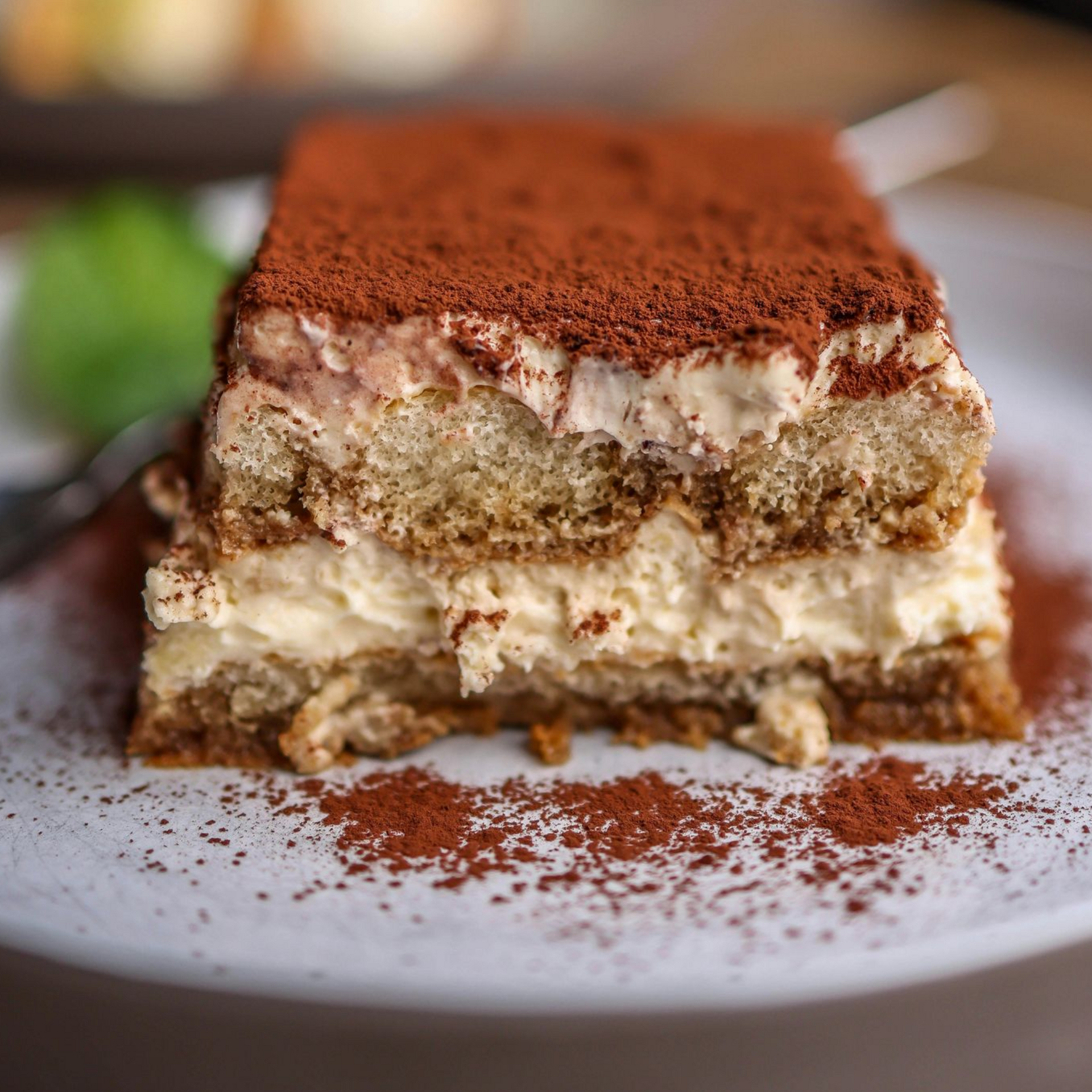 Primo piano di una fetta di tiramisù al piatto che evidenzia la consistenza densa e vellutata della crema al mascarpone.