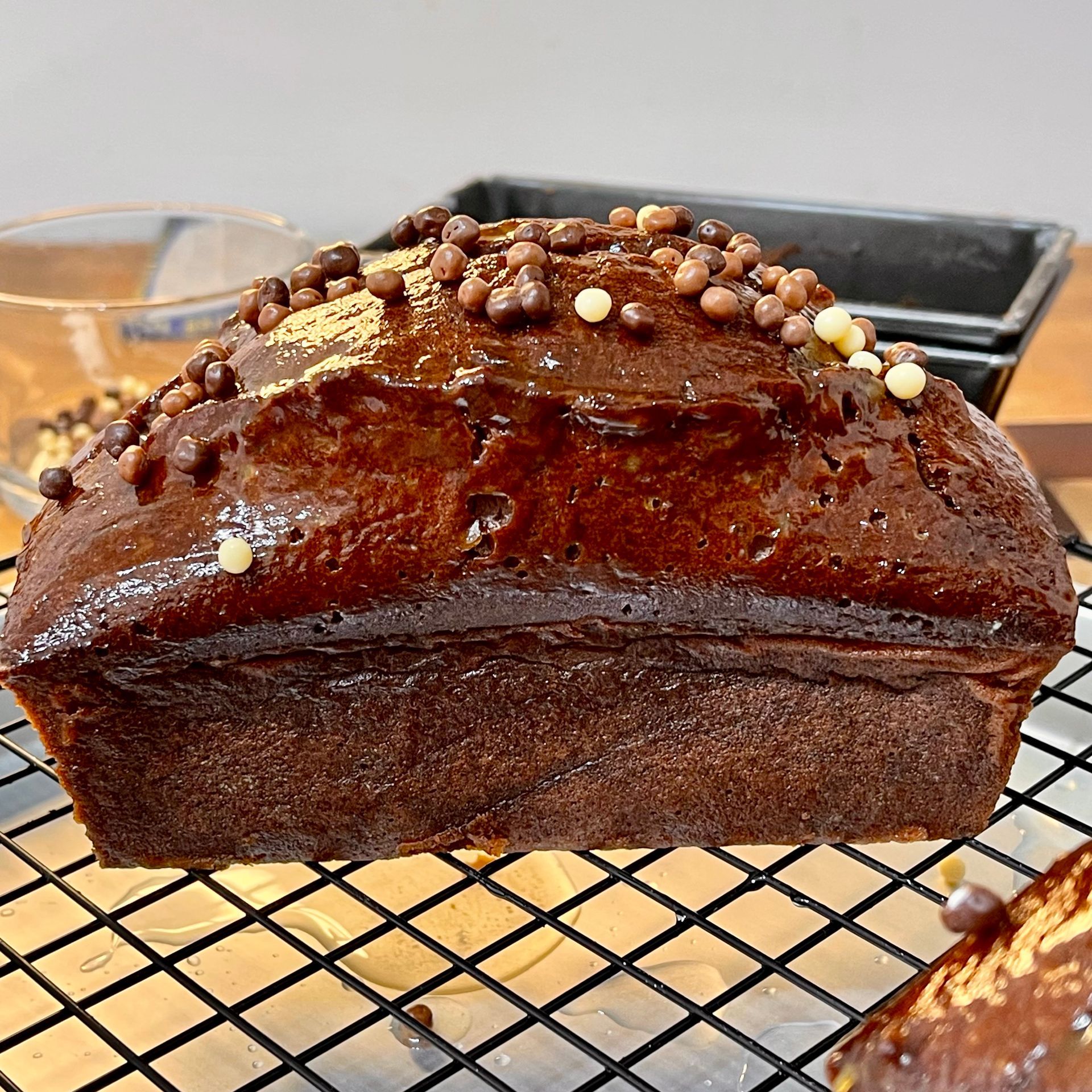 Plumcake al cioccolato soffice intero, appena sfornato su una griglia e lucidato con confettura
