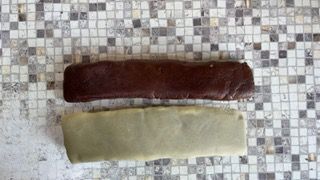 Due pezzi di cioccolato e un pezzo di pasta verde sono appoggiati su un tavolo.