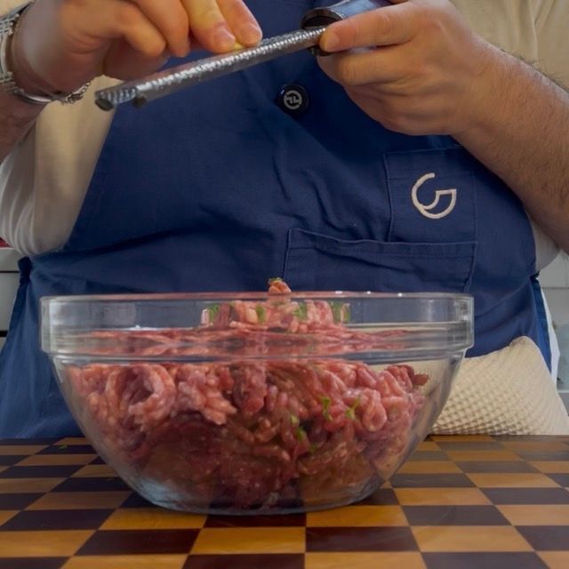 Grattugiatura di una punta di aglio fresco direttamente sul mix di carne macinata.