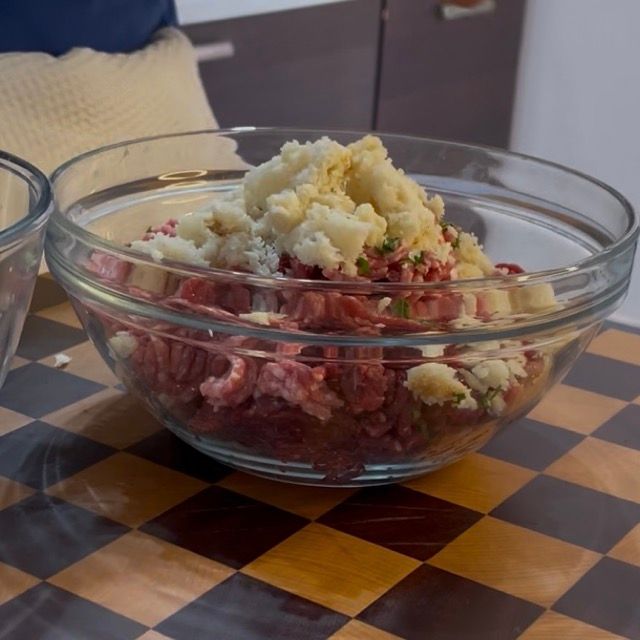 Inserimento del pane strizzato nella ciotola con la carne macinata.