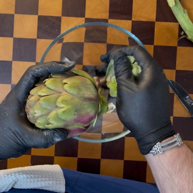 Taglio del gambo lungo e rimozione delle foglie esterne più dure e coriacee del carciofo.