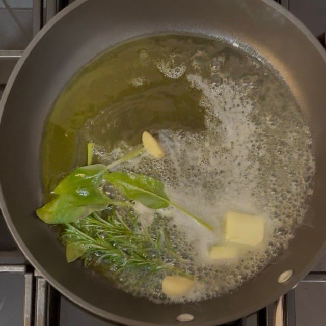 Inserimento degli aromi nel fondo: spicchio d'aglio, rametto di rosmarino e foglie di salvia.