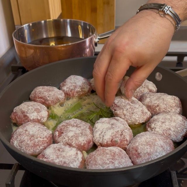 Posizionamento delle polpette infarinate nella padella calda con gli aromi.