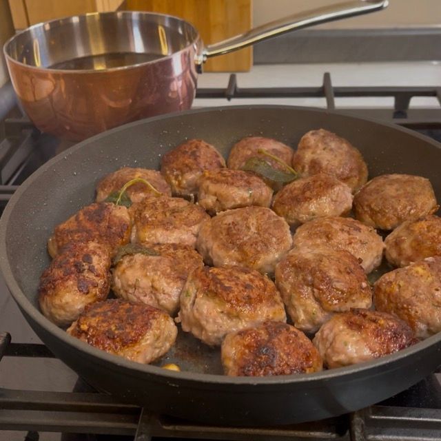 Rotazione delle polpette con una pinza da cucina per dorare uniformemente tutti i lati.