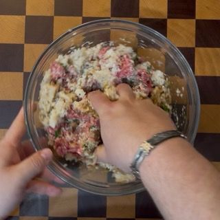 Lavorazione manuale degli ingredienti all'interno della ciotola per amalgamare i sapori.