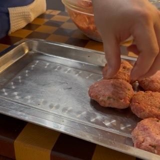 Disposizione ordinata di tutte le polpette di carne modellate sopra un vassoio.
