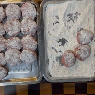 Dettaglio delle polpette infarinate sul vassoio, passaggio fondamentale per addensare le polpette sfiziose in padella.