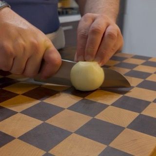 Taglio a metà di una cipolla bianca pulita sopra un tagliere per le nostre polpette ricette.