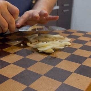 Affettatura sottile della cipolla per creare la base aromatica del sughetto.