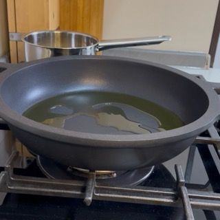 Preparazione del fondo di cottura in una padella capiente con un filo d'olio extravergine d'oliva.