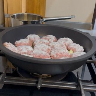 Posizionamento delle polpette infarinate nella padella calda per fare le polpette di carne morbide in padella.