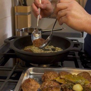Reinserimento delle polpette dorate nel tegame sopra il letto di cipolle stufate.