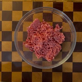 Carne macinata di vitella fresca inserita sul fondo di una ciotola pulita per le polpette di carne.