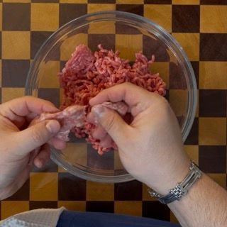 Incisione e rimozione manuale della pelle esterna da una salsiccia fresca.