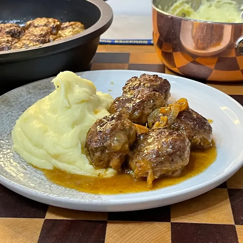 Un piatto da portata rustico colmo di polpette di carne della nonna morbide e succose, decorate con una foglia di basilico fresco per presentare la nostra esclusiva polpette ricetta.