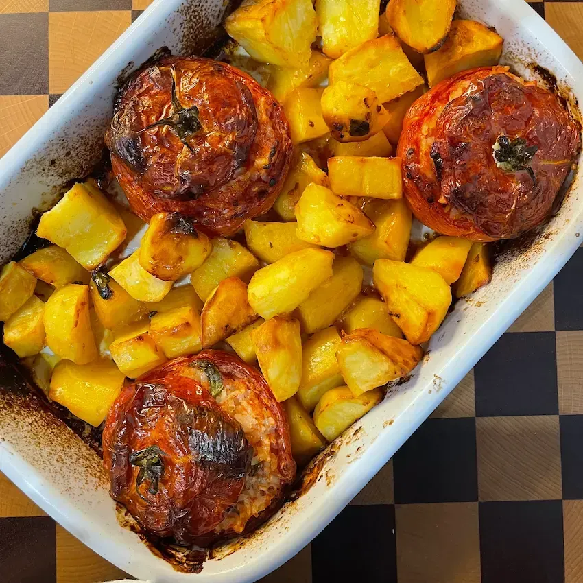 Teglia di pomodori con riso e patate al forno dorate. Ricetta dei pomodori con riso alla romana