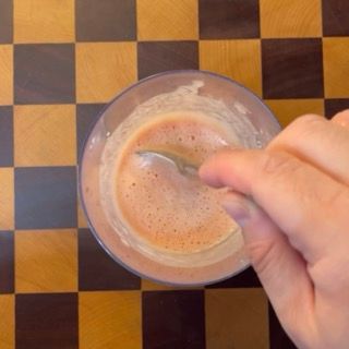 Mescolamento vigoroso con un cucchiaio per distribuire bene aglio, erbe e olio nella salsa di pomodoro.